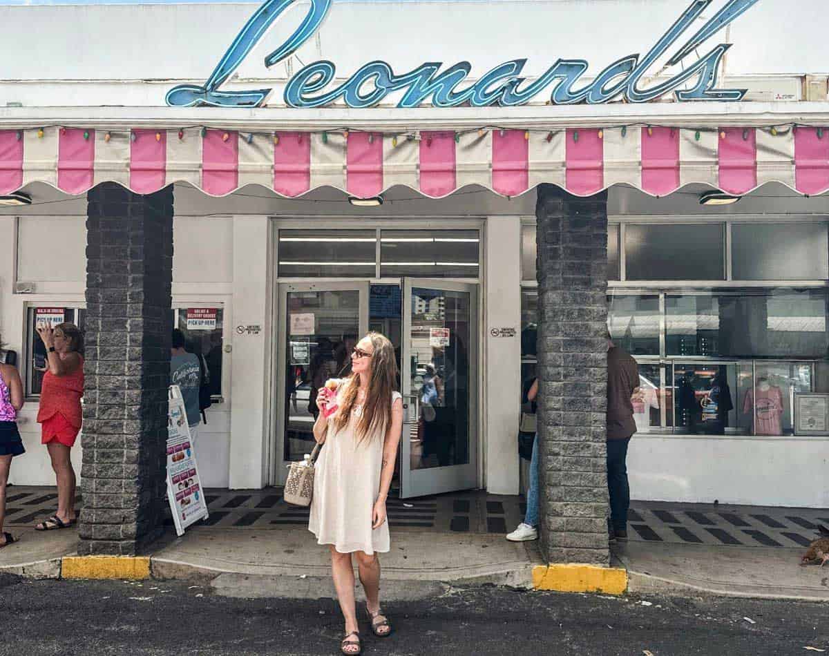 a girl standing in front of the entrance to famous malasadas place called leonards' in Waikiki.