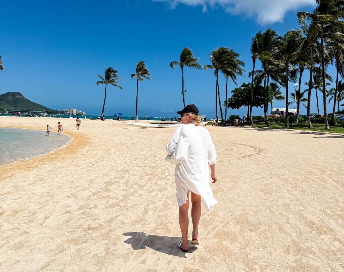 a girl walking on the beach in ala moana waikiki, oahu, hawaii.