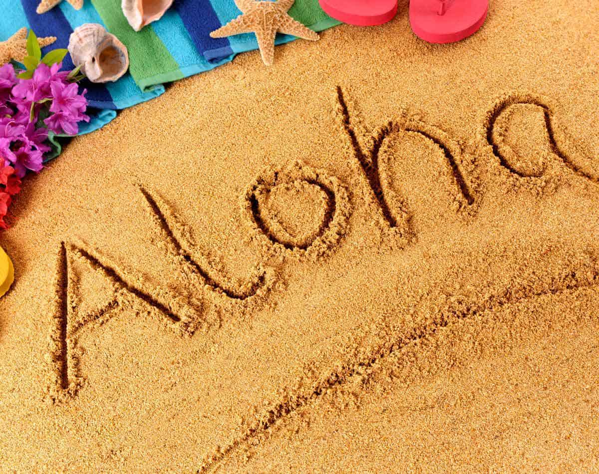 word aloha written on sandy beach.